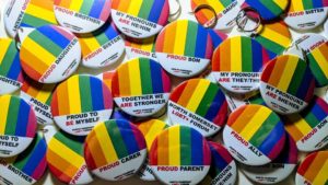 A pile of badges with rainbow colouring celebrating Pride Month